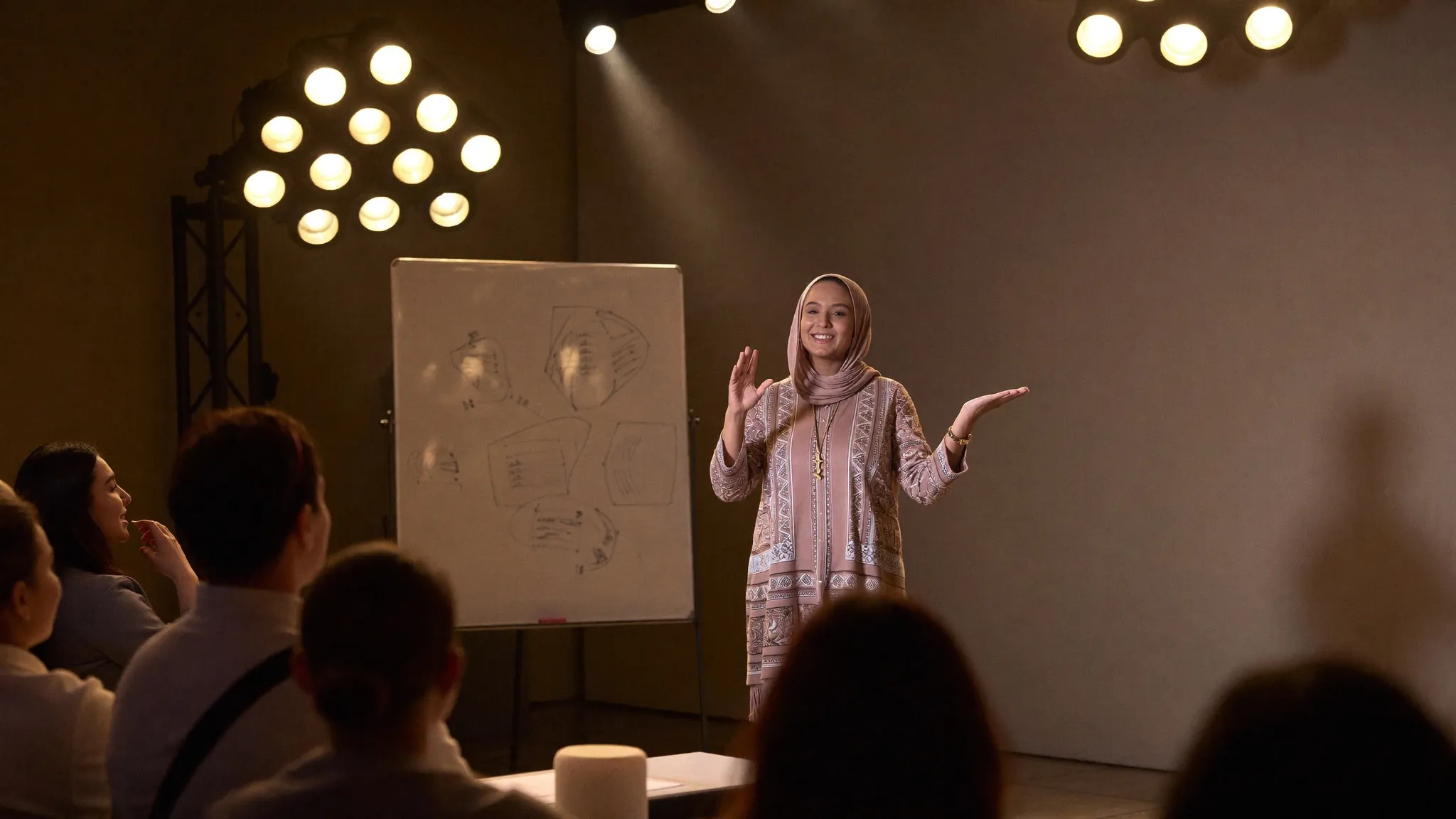 Humna Raza speaking to a small audience beside a whiteboard.